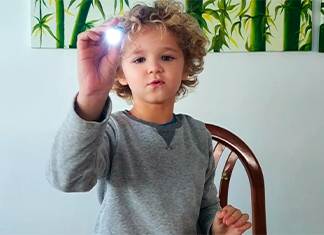 niño apuntando con una linterna para un experimento de luz