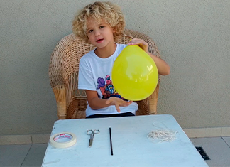 niño con globo sobre una mesa con materiales para experimento