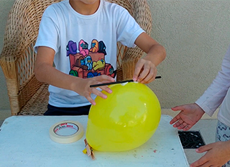 niño poniendo una pajita en un globo