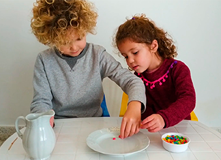 niños poniendo confites en un plato en un experimento fácil