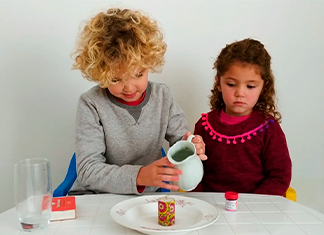 niño sirve agua en un plago con vela