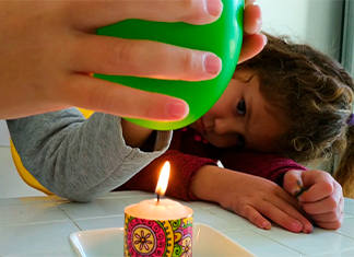 niña mirando un globo encima de la vela en un experimento fácil