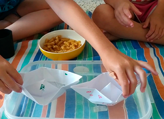 dos barquitos de papel en un recipiente con agua del juego de mesa casero