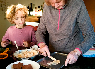 abuela enseña al niño como poner crema en un recipiente