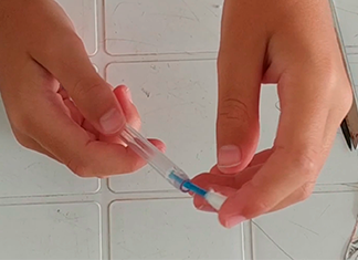 manos que ponen un isopo en una lapicera simulando lápiz táctil