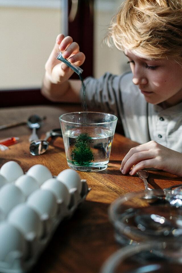 niño vuelca colorante en un vaso con agua para experimentos de mezclas