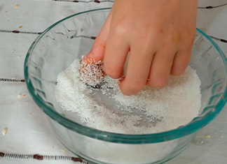mano rodando la trufa en un bowl de coco rayado
